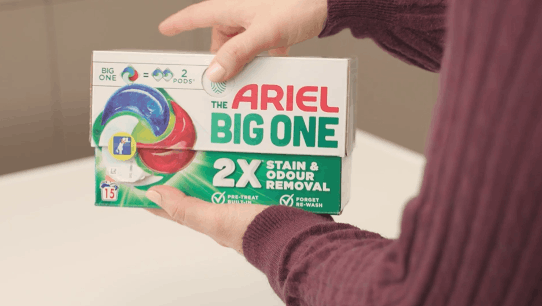 Una persona sostiene una caja de Ariel PODS® The Big One, con el mensaje 2X Stain & Odour Removal.
